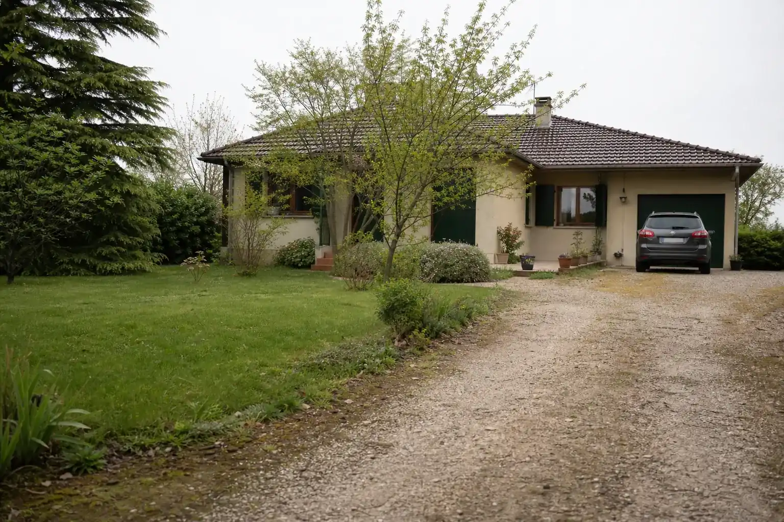 Pavillon de la fin des années soixante-dix, garage accolé, allée de gravier et pelouse
