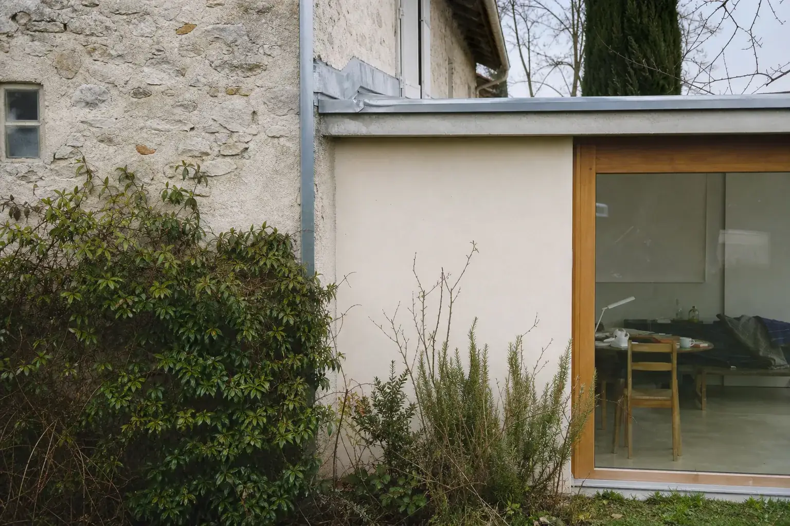 Raccord entre une maison enduite ancienne et une extension neuve, joint de zinc vertical